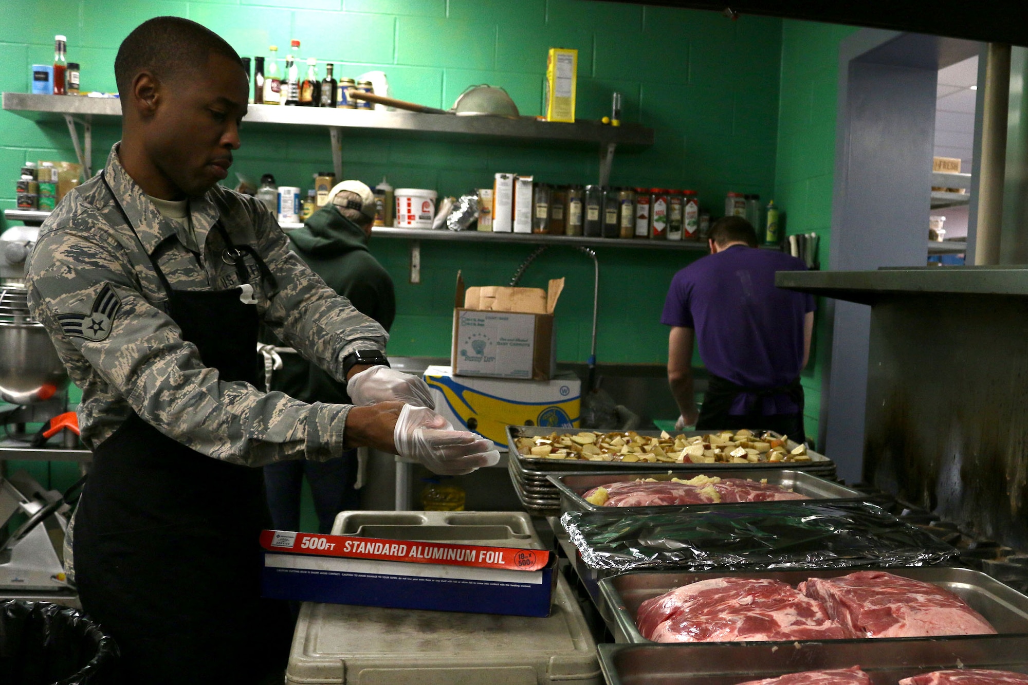 Senior Airman Terry Raglin, aviation research management (SARM) for the 89th Airlift Squadron, puts on gloves to prepare food at the House of Bread Dec. 8, 2019. Raglin along with nine Airmen from his squadron, prepped eggs, potatoes, vegetables and desserts. (U.S. Air Force photo/Staff Sgt. Joel McCullough)