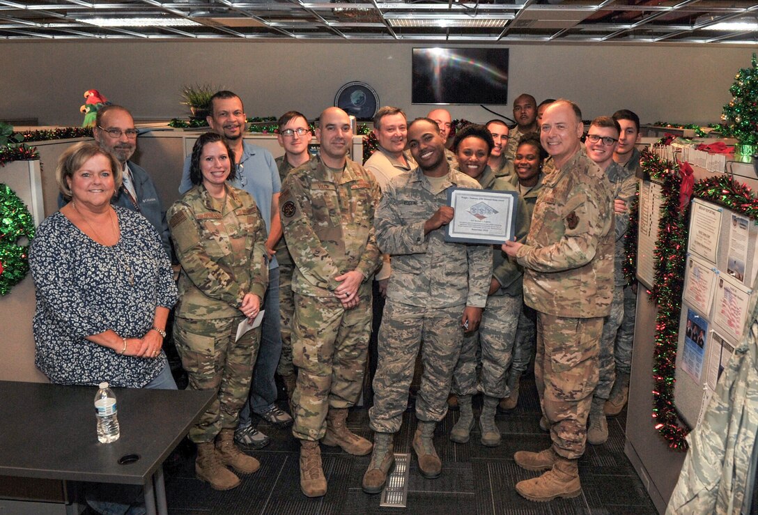 Airman 1st Class Bendali Eugene, Communications Information Group knowledge manager, is presented with the Diamond Sharp Award by First Sgts Senior Master Sgt. William Schipper and Master Sgt. Juan Villa at the National Air and Space Intelligence Center on Wright-Patterson Air Force Base, Ohio, Dec. 18, 2019. The Diamond Sharp Award recognizes Airmen who have actively demonstrated their commitment to Air Force values or have gone above and beyond in helping others. (U.S. Air Force photos by Staff Sgt. Seth Stang)