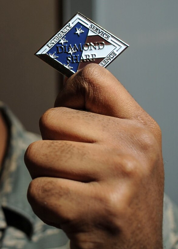 Airman 1st Class Bendali Eugene, Communications Information Group knowledge manager, is presented with the Diamond Sharp Award by First Sgts Senior Master Sgt. William Schipper and Master Sgt. Juan Villa at the National Air and Space Intelligence Center on Wright-Patterson Air Force Base, Ohio, Dec. 18, 2019. The Diamond Sharp Award recognizes Airmen who have actively demonstrated their commitment to Air Force values or have gone above and beyond in helping others. (U.S. Air Force photos by Staff Sgt. Seth Stang)