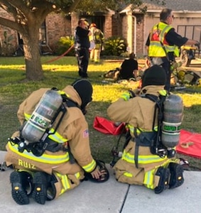 Two firefighters from Joint Base San Antonio-Fort Sam Houston prepare to enter a house in Kirby, Texas, located northeast of San Antonio, during a recent fire.