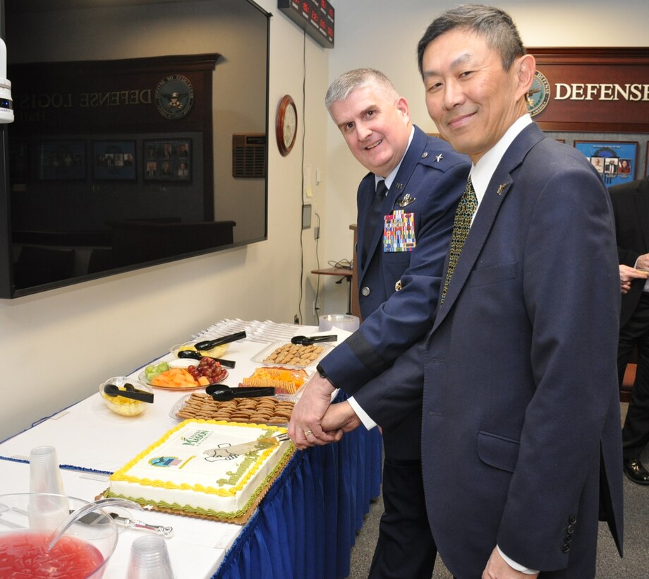 Two men cut a cake together.