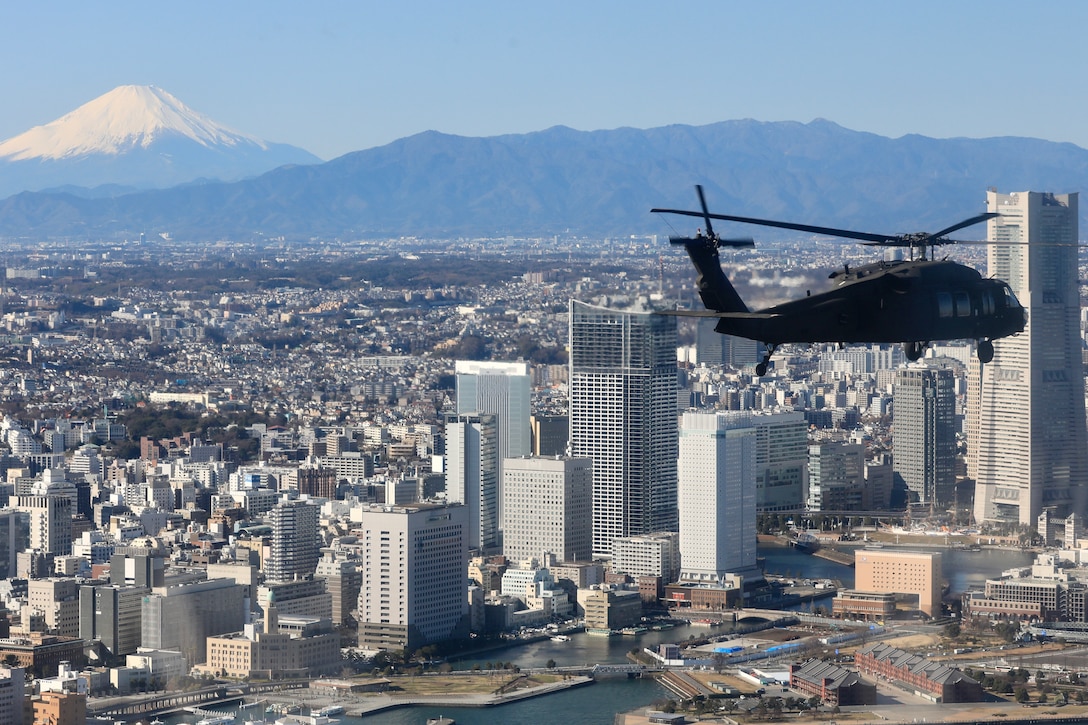 A military helicopter flies above a city in Japan.