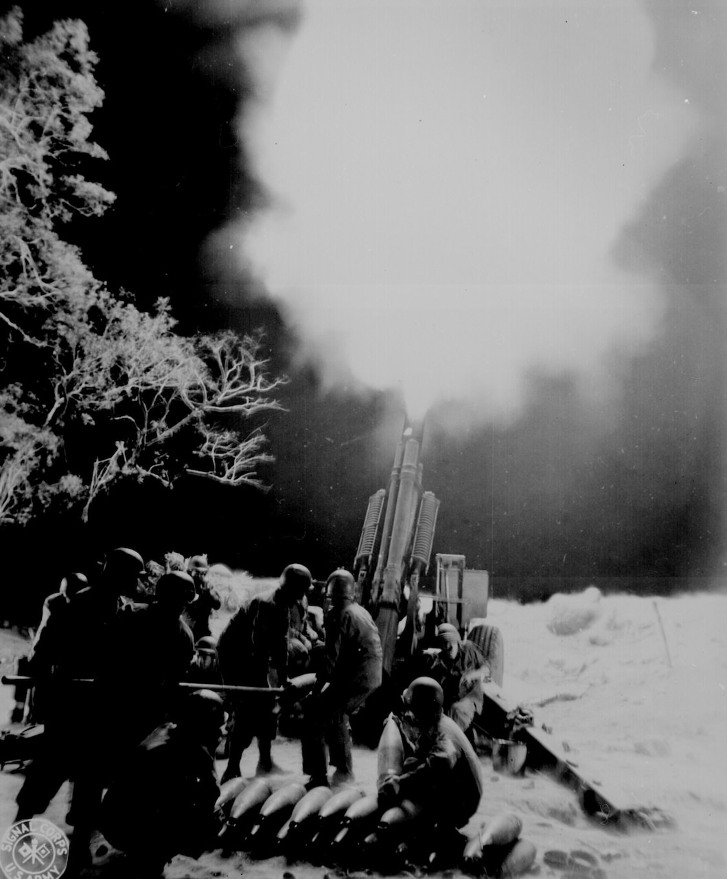 Soldiers fire a large gun at night.