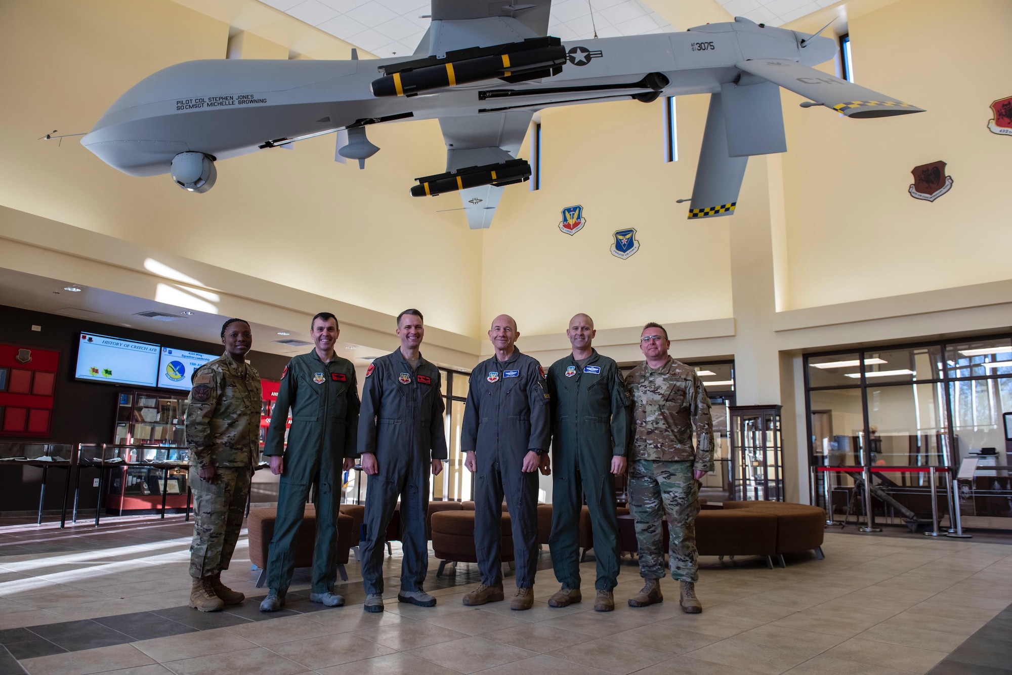 Air Combat Command leadership stand with 432nd Wing Leadership for a group photo under an MQ-1 Predator.
