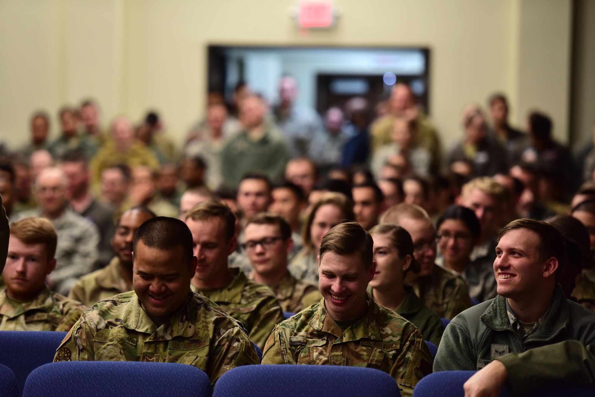 Airmen laugh in a crowd at an all-call.