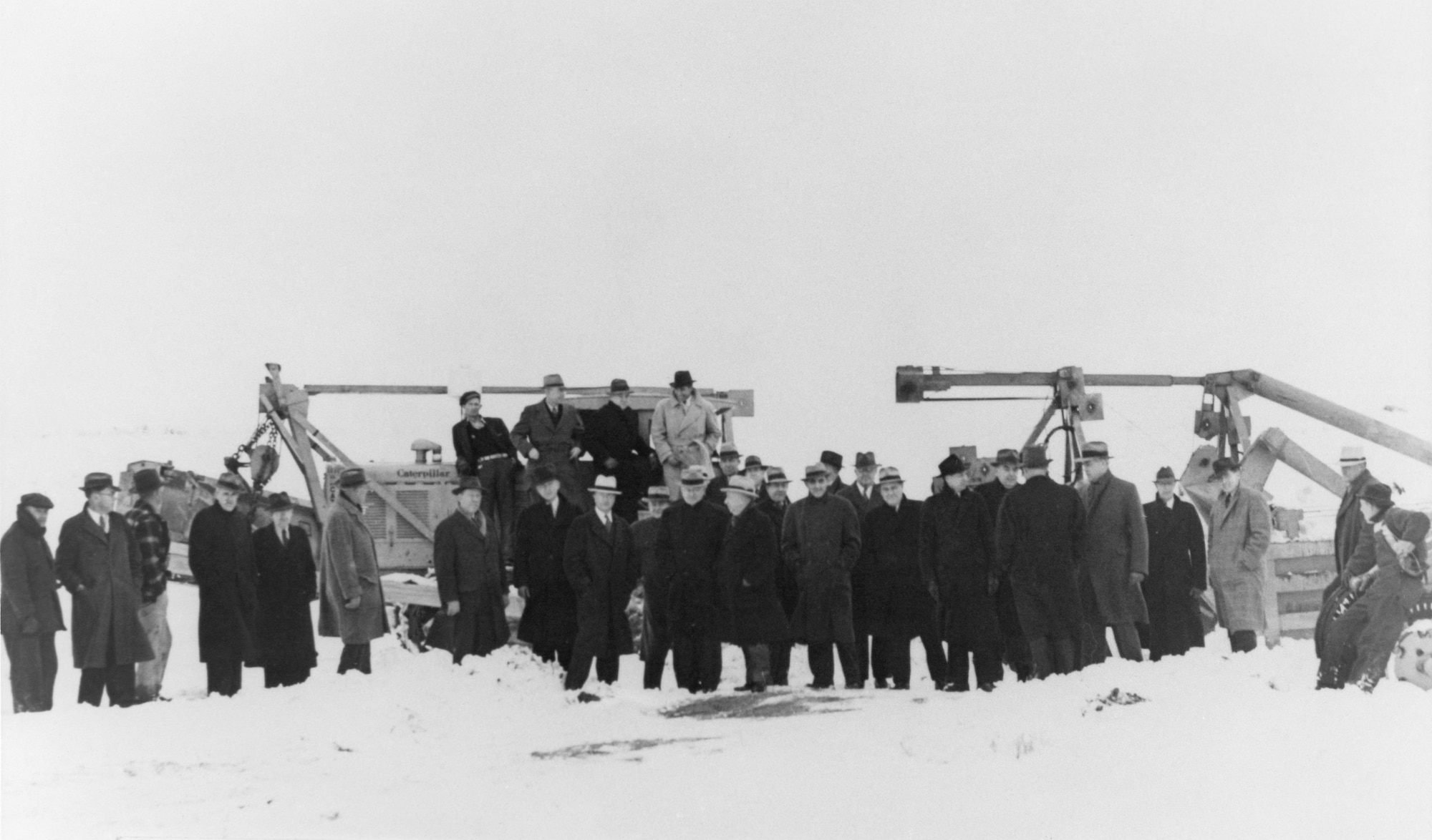 A black and white photo of several base and community officials gathering during the ground breaking of Hill Field on a snowy day Jan. 12, 1940.