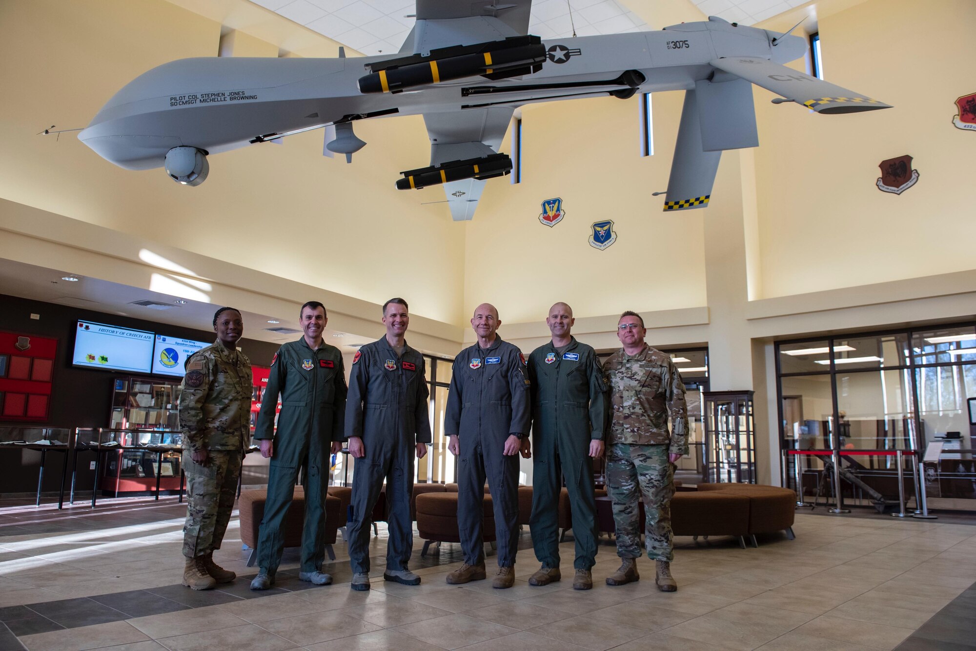 Air Combat Command leadership stand with 432nd Wing Leadership for a group photo under an MQ-1 Predator.