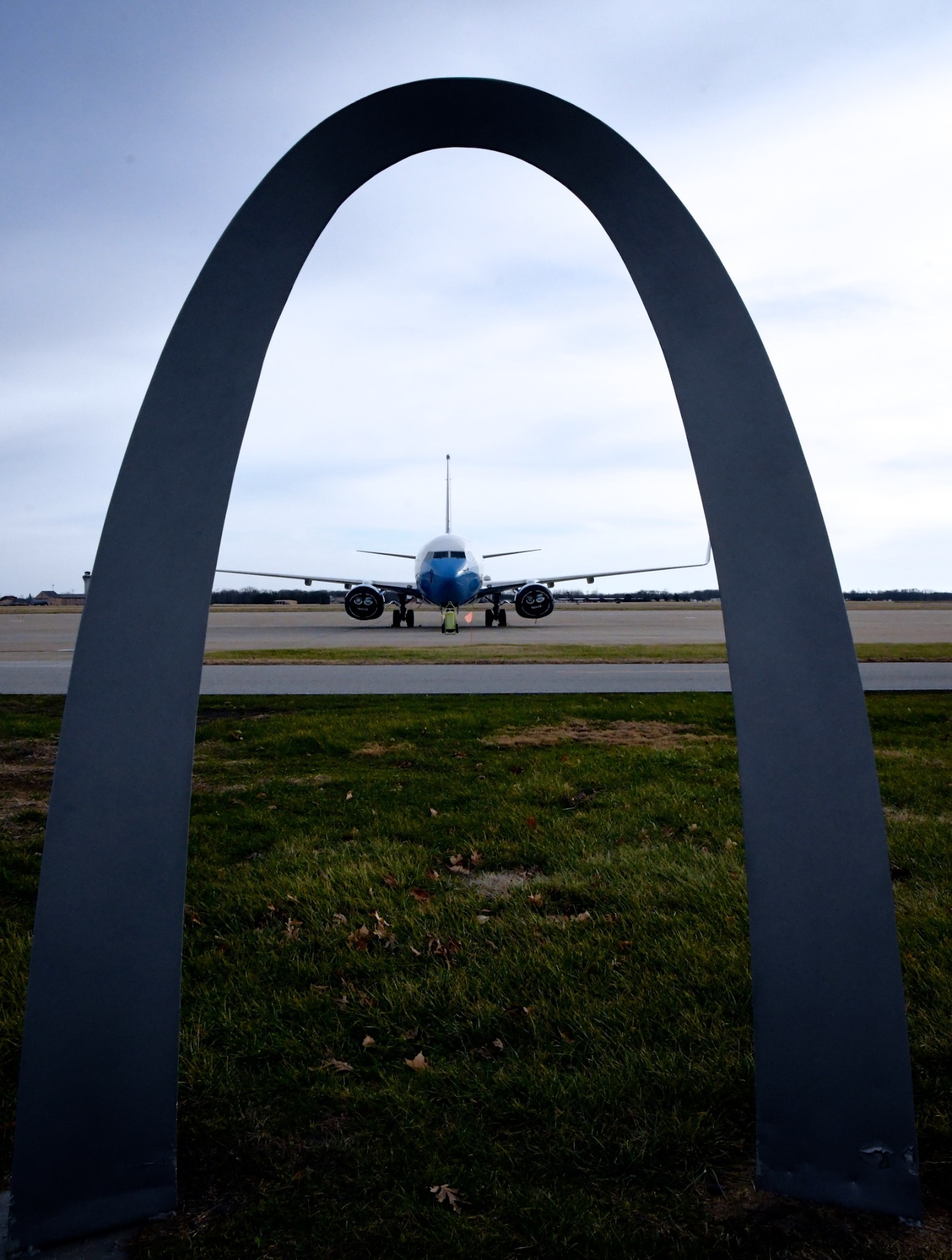 An Air Force Reserve Command C-40C aircraft sits ready for another mission, framed by a replica of the Gateway Arch at Scott Air Force Base, Ill..  The 932nd Airlift Wing's Maintenance Group is responsible for training Airmen to inspect, maintain and repair Air Force Reserve Command C-40C planes. The 932nd MXG's management enables the 932nd Operations Group's pilots to fly distinguished visitor (DV) airlift around the world, anywhere they are needed by the nation's leaders. Here, several maintainers prepare to make inspection checks on the plane on a windy winter day, January 2, 2020 at Scott Air Force Base, Ill. The Illinois unit, which is part of 22nd Air Force, under Air Force Reserve Command, flies four of the C-40C planes worldwide. The unit is known as the "Gateway Wing" among Air Force Reserve units.  (U.S. Air Force photo by Lt. Col. Stan Paregien)