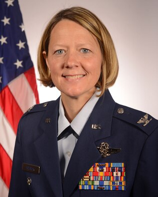 Picture shows Col. Amy Holbeck handing out small boxes of treats to Airmen.