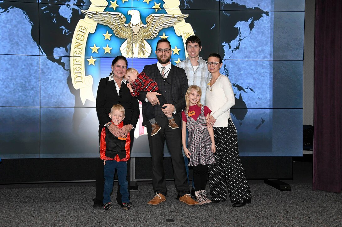 Four adults and three kids stand on stage