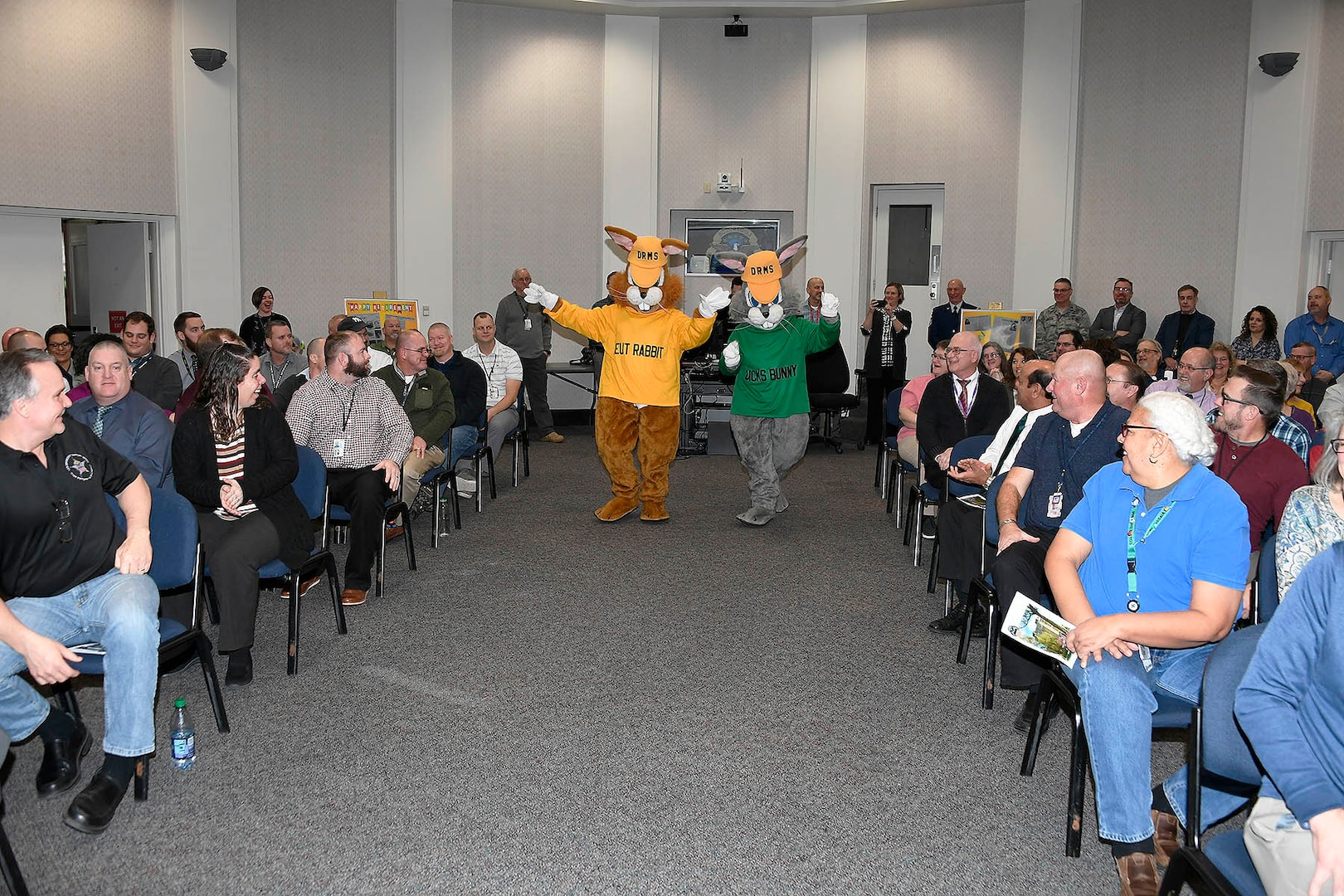 a yellow and green shirt mascot walk down the isle in the audience