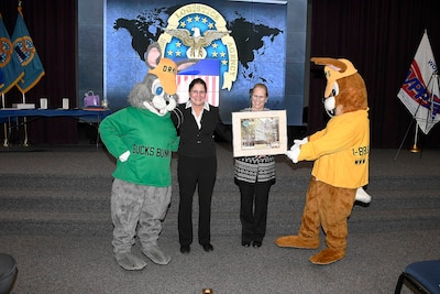 Mascots stand with Sherry Low and lady holding a picture