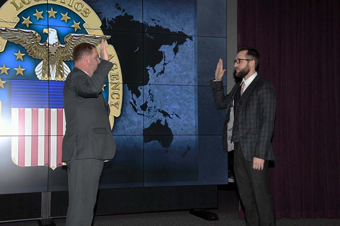 two men facing each other on stage with their right hands raised