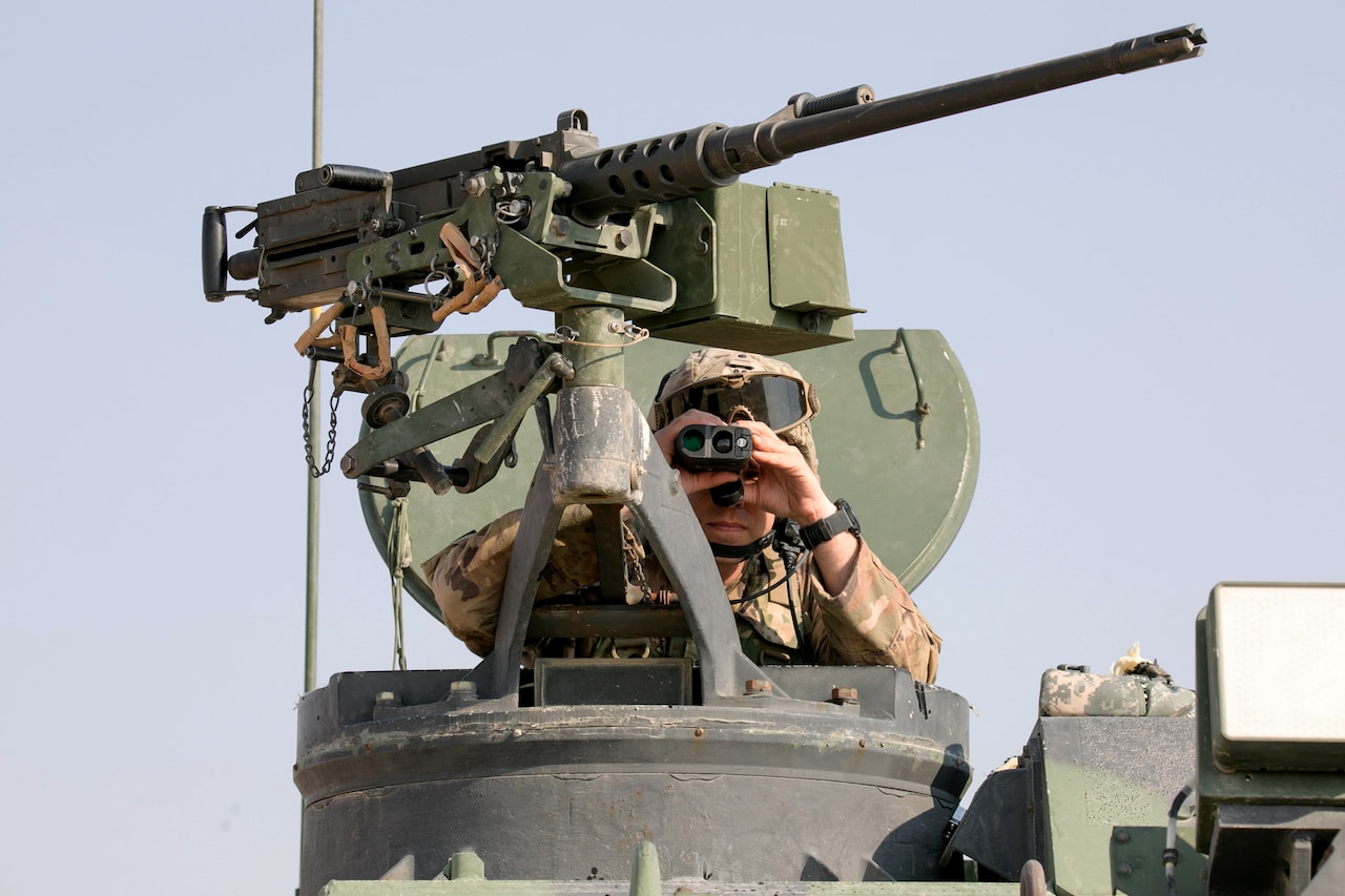 A soldier looks through binoculars.