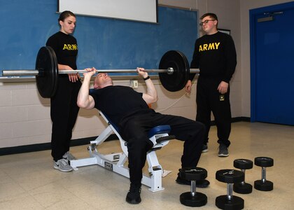 Army ROTC Cadet Felicia L. Showers, left, and New York Army National Guard Staff Sgt. Jeffery A. Barker, center, both from the 10th Mountain Division (LI) Main Command Post – Operational Detachment, demonstrate how to perform a supine chest press during Army Combat Fitness Test training in Syracuse, N.Y., Nov. 17, 2019. The ACFT replaces the Army Physical Fitness Test in October 2020.