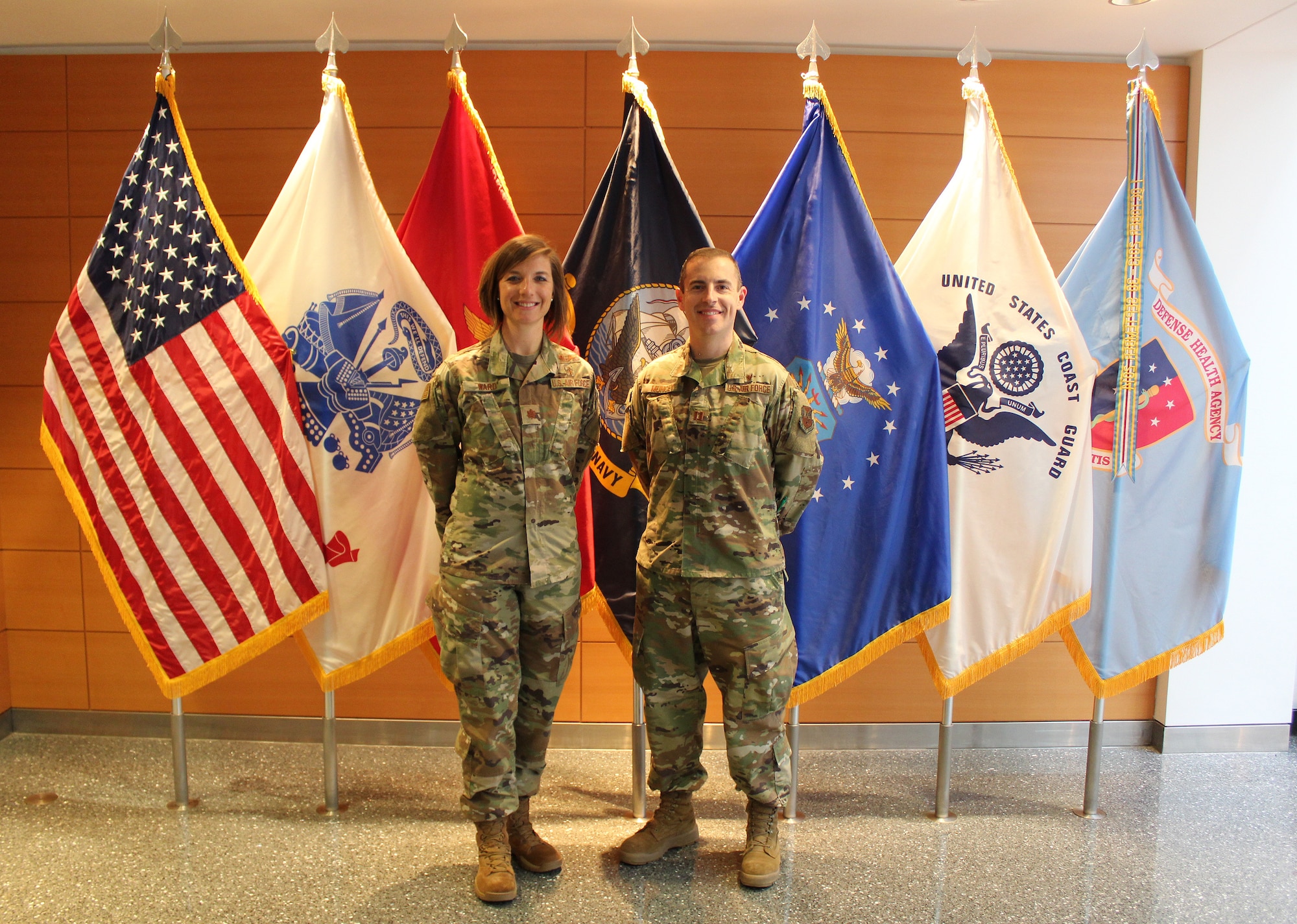 Image of two Airmen standing in front of flags.