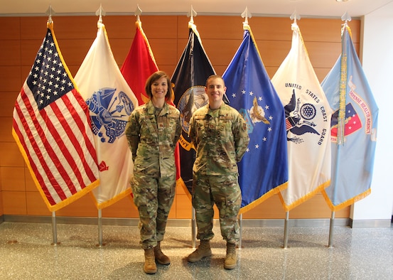 Image of two Airmen standing in front of flags.