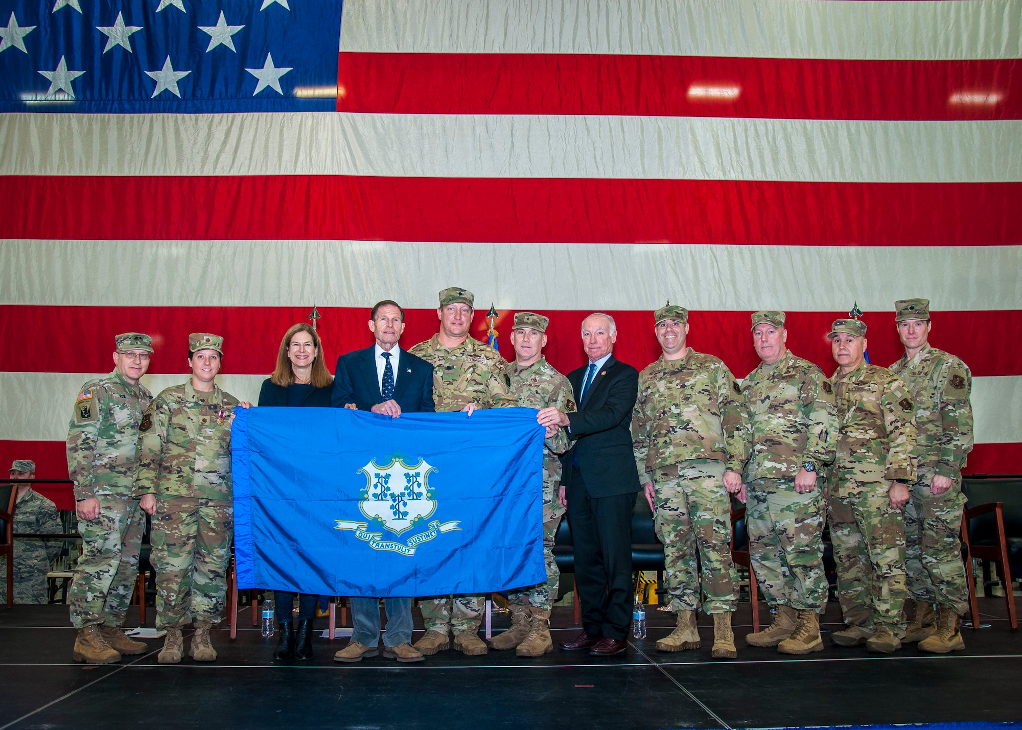 Lt. Col. John Saunders and Maj. Cheryl Mead, leadership for the recently deployed 103rd Operations and Maintenance Groups, along with Maj. Gen. Francis Evon, The Adjutant General of the Connecticut National Guard, U.S. Senator Richard Blumenthal, U.S. Representative Joe Courtney, and Connecticut Air National Guard leadership, present a Connecticut state flag to Lt. Gov. Susan Bysiewicz during a Freedom Salute ceremony at Bradley Air National Guard Base, East Granby, Conn. Jan. 4, 2020. The flag flew over Syria during a combat mission on a Connecticut Air National Guard C-130 Hercules aircraft. (Photo by Tim Koster, Connecticut National Guard Joint Force Headquarters Public Affairs)