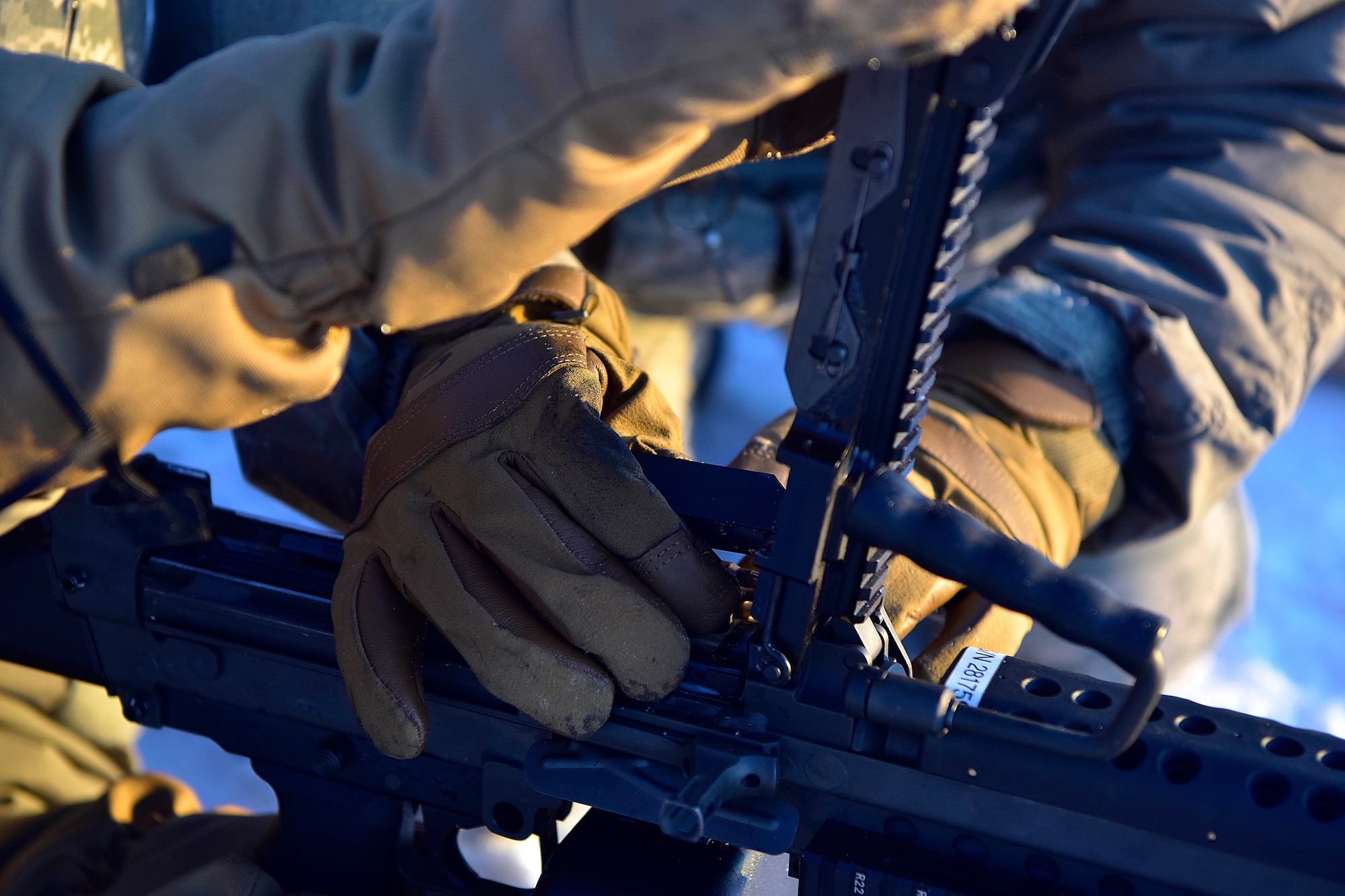 Two 354th Security Forces Squadron Airmen load a M-249 Squad Automatic Weapon with prototype cold weather gloves at Eielson Air Force Base, Alaska, Jan. 9, 2020. Even in minus 40 degrees, Security Forces Airmen must be able to use their hands to operate their weapon systems. (U.S. Air Force photo by Senior Airman Beaux Hebert)