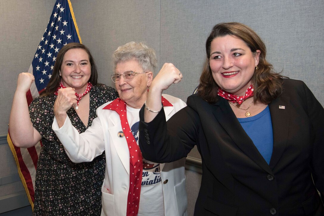 Three people stand in a row, flexing their muscles.