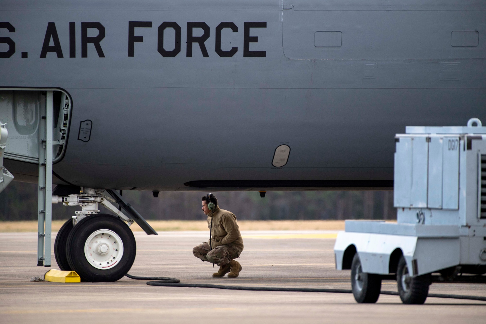 U.S. Air Force Staff Sgt. Jose A. Reyes, a 911th Air Refueling Squadron (ARS) dedicated crew chief, squats near a KC-135 Stratotanker, during pre-flight checks before takeoff from Seymour Johnson Air Force Base, North Carolina, Dec. 12, 2019. The 911 ARS prepared for their final mission on a KC-135 Stratotanker. (U.S. Air Force photo by Staff Sgt. Mary McKnight)