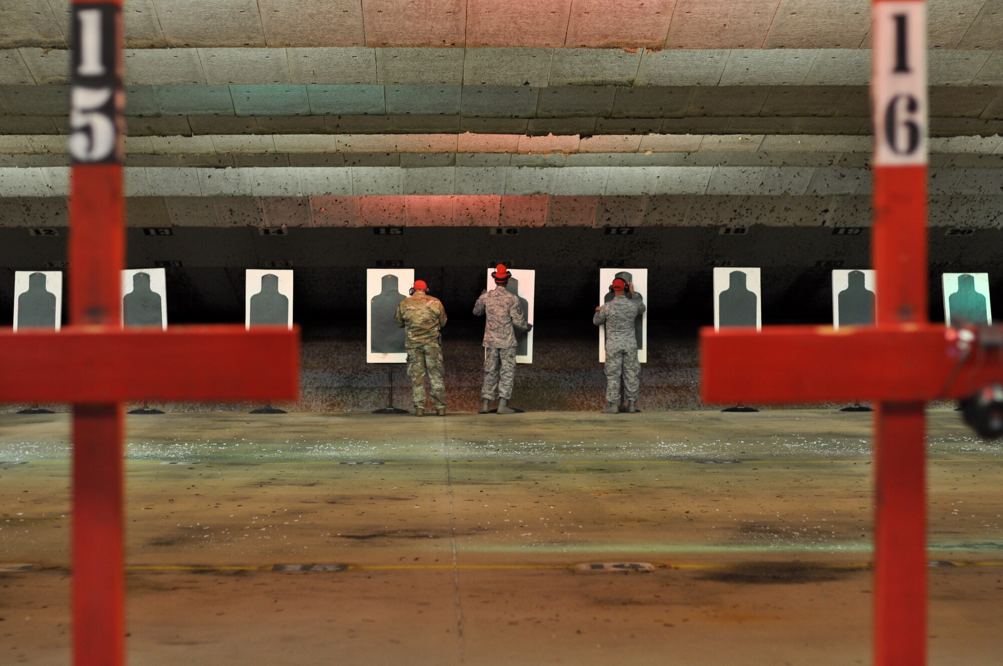 From left, Senior Airman Emilio San Miguel, Master Sgt. Henry Relf and Tech. Sgt. Shannon Jones, 908th Security Forces Squadron Combat Arms instructors, stand in front of the targets, Nov. 2, 2019, in the firing bay at Maxwell AFB, Alabama. After every round of firing, the instructors secure the lanes so that they can review each target in order to instruct Airmen on how to improve. (U.S. Air Force photo by Airman 1st Class Shelby S. Thurman)