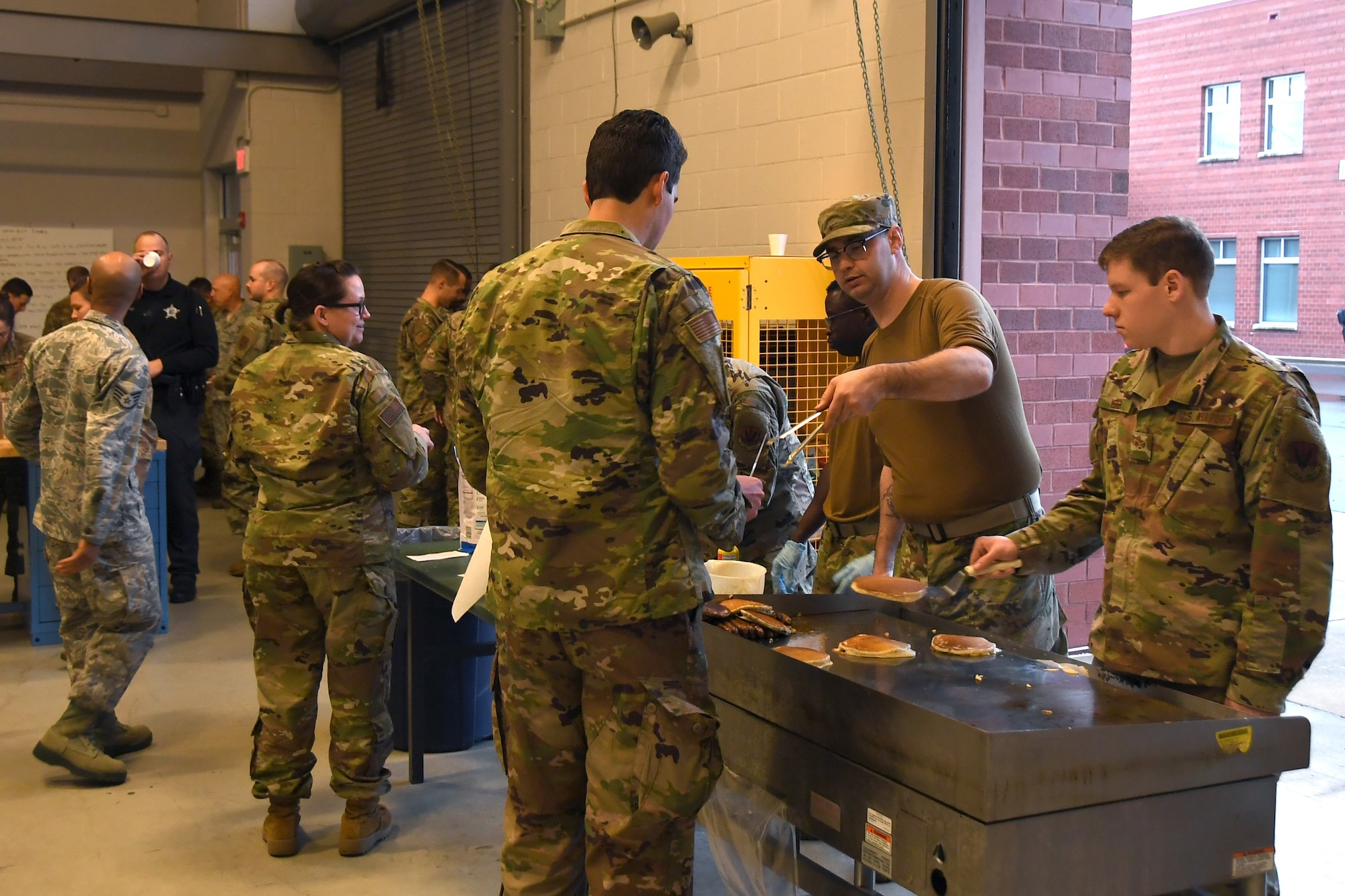 U.S. Air Force Senior Airman Robert Hartley (left), and other Airmen cook pancakes on a grill during a breakfast fundraiser, Jan. 12, 2020 at the 235th Air Traffic Control Squadron in New London, N.C. Members of the North Carolina Air National Guard as well as local airport authorities and law enforcement were invited to participate in a pancake breakfast social in order to strengthen community ties and build new relationships while raising funds for Morale, Welfare and Recreation.