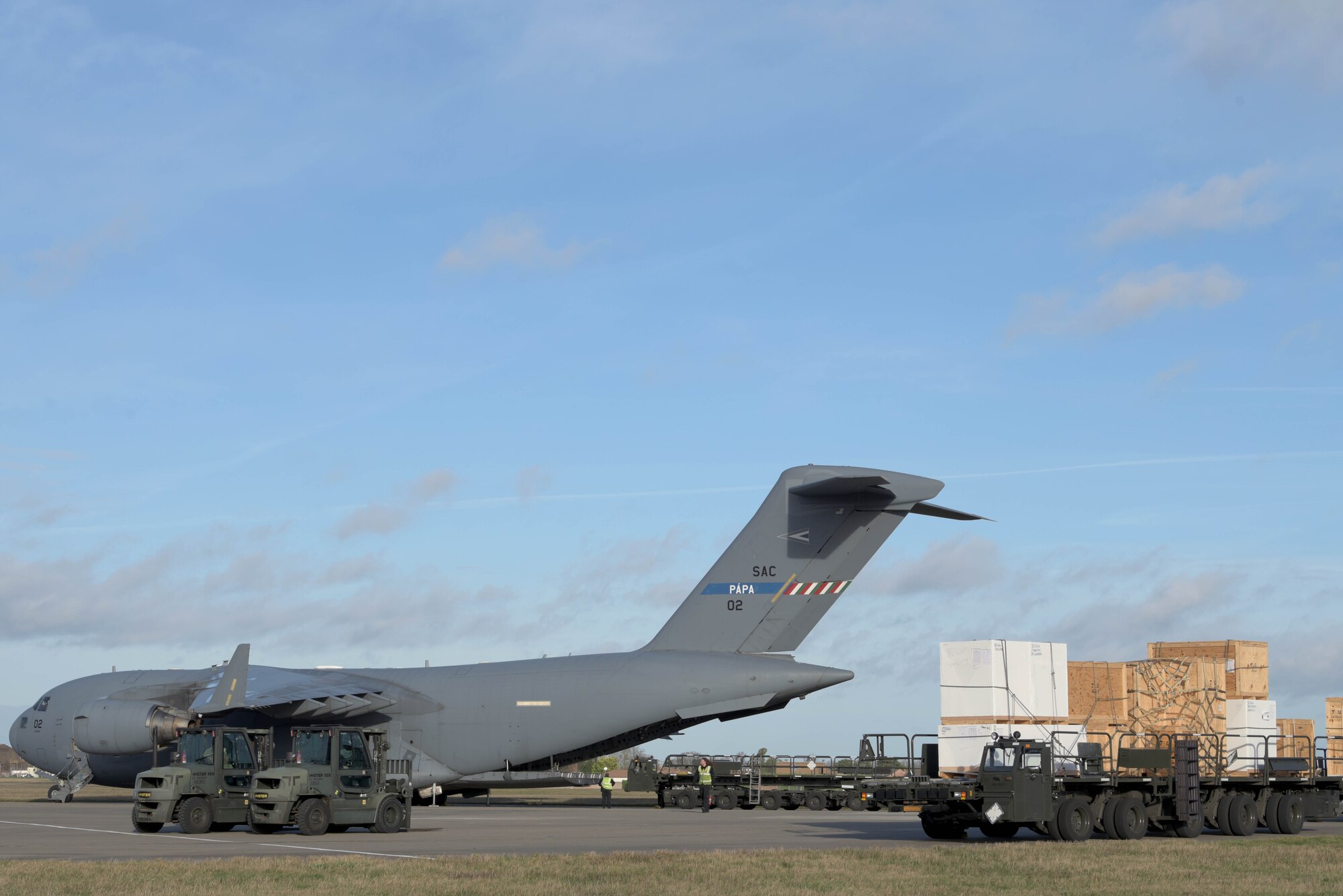 Civilians assigned to the 727th Air Mobility Squadron unload the Boom Operator Weapon System Trainer from a C-17 Globemaster III assigned to the Heavy Airlift Wing, Pápa Air Base, Hungary, at RAF Mildenhall, England, Jan. 11, 2020. The BOWST system enables instructors to test students in a wide variety of scenarios while receiving real-time information on the student's progress, in a safe environment. (U.S. Air Force photo by Senior Airman Benjamin Cooper)