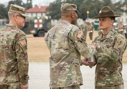 While Lt. Gen. James E. Rainey (left) looks on, Drill Sergeant David Nagel (right), U.S. Army Medical Center of Excellence Best Medic of the Year, presents Maj. Gen. Patrick D. Sargent the shell from the last round of salute as a memento of the change of command ceremony.