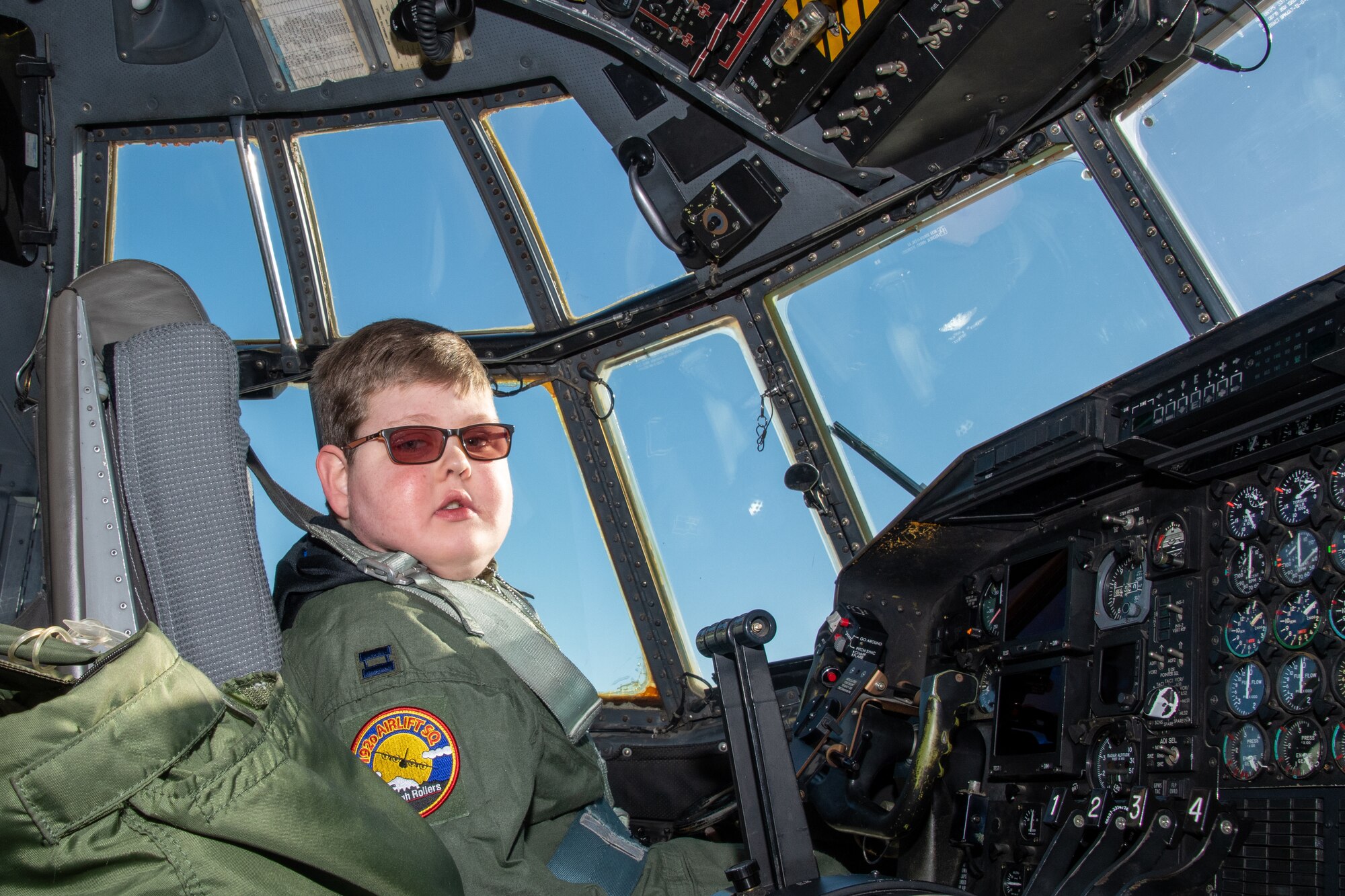 Capt. Tennison 'Wizard' Hunter, the pilot for a day from the 152nd Airlift Wing, Nevada Air National Guard,  poses for a photo in a C-130 Hercules cockpit Dec. 16, 2019. The Pilot for a Day program aims to support children with lifelong disabilities by welcoming them into the wing's military family and providing the child with the experience in being a U.S. Air Force pilot. (U.S. Air National Guard photo by Senior Airman Matthew Greiner)