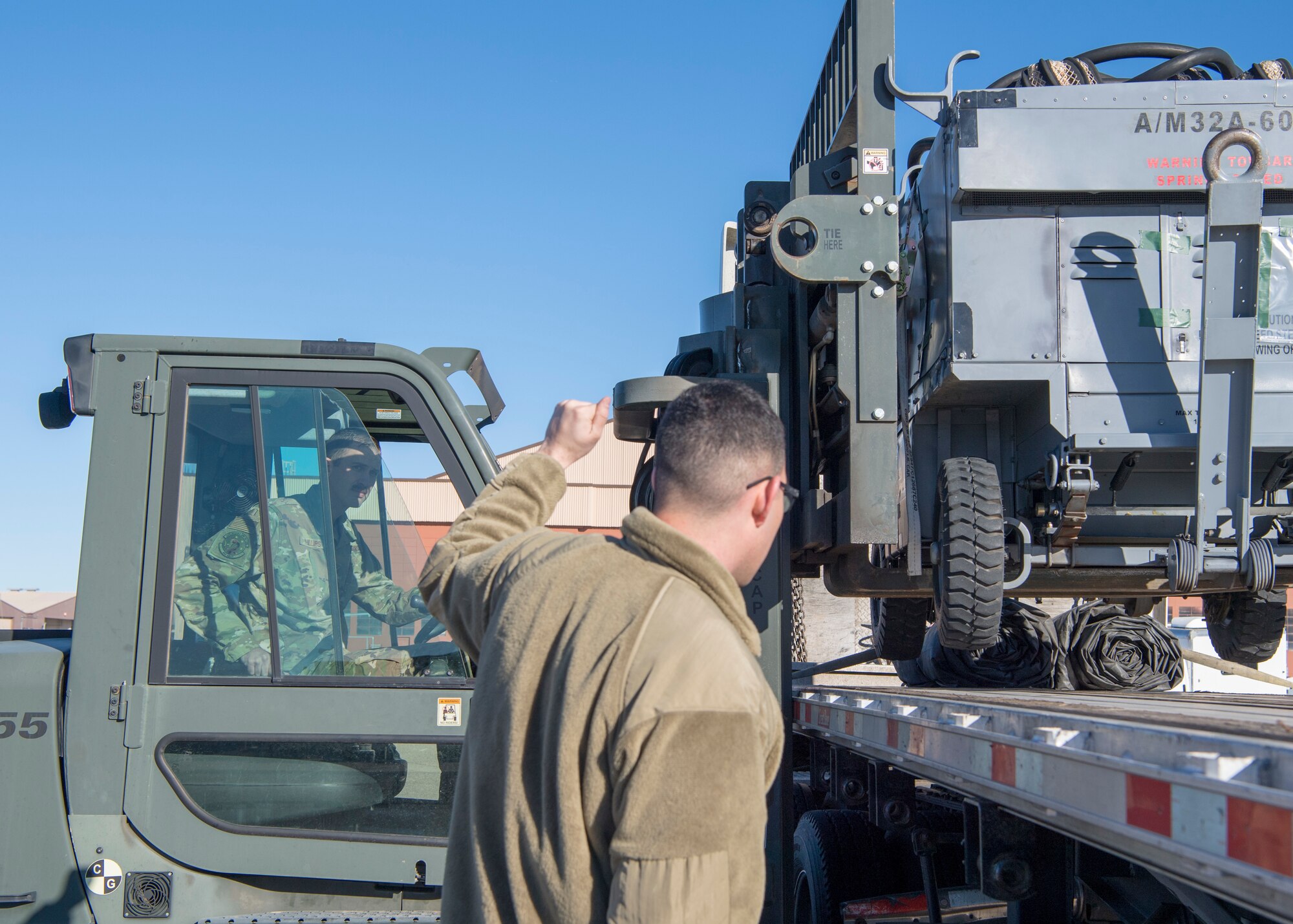 Staff Sgt. Dustin Phillips, 311th Aircraft Maintenance Unit support non-commissioned officer in charge, drives a forklift while Staff Sgt. Andrew Marsh, 311th AMU lead support technician, gives directions on loading a ground power unit onto the semi-truck, Jan. 6, 2020, on Holloman Air Force Base, N.M. Airmen from the maintenance group loaded cargo that was integral to the 311th Fighter Squadron's mission in Key West, Fla. (U.S. Air Force photo by Airman 1st Class Autumn Vogt)