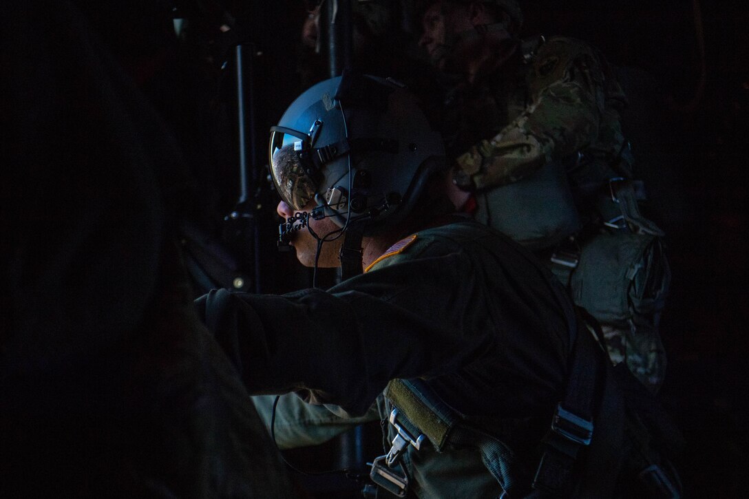 Loadmaster looks out side door aboard flying C-130J Super Hercules.