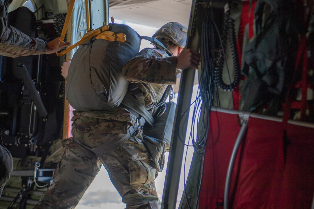 Soldier leans out side door midair aboard U.S. Air Force C-130J Super Hercules.
