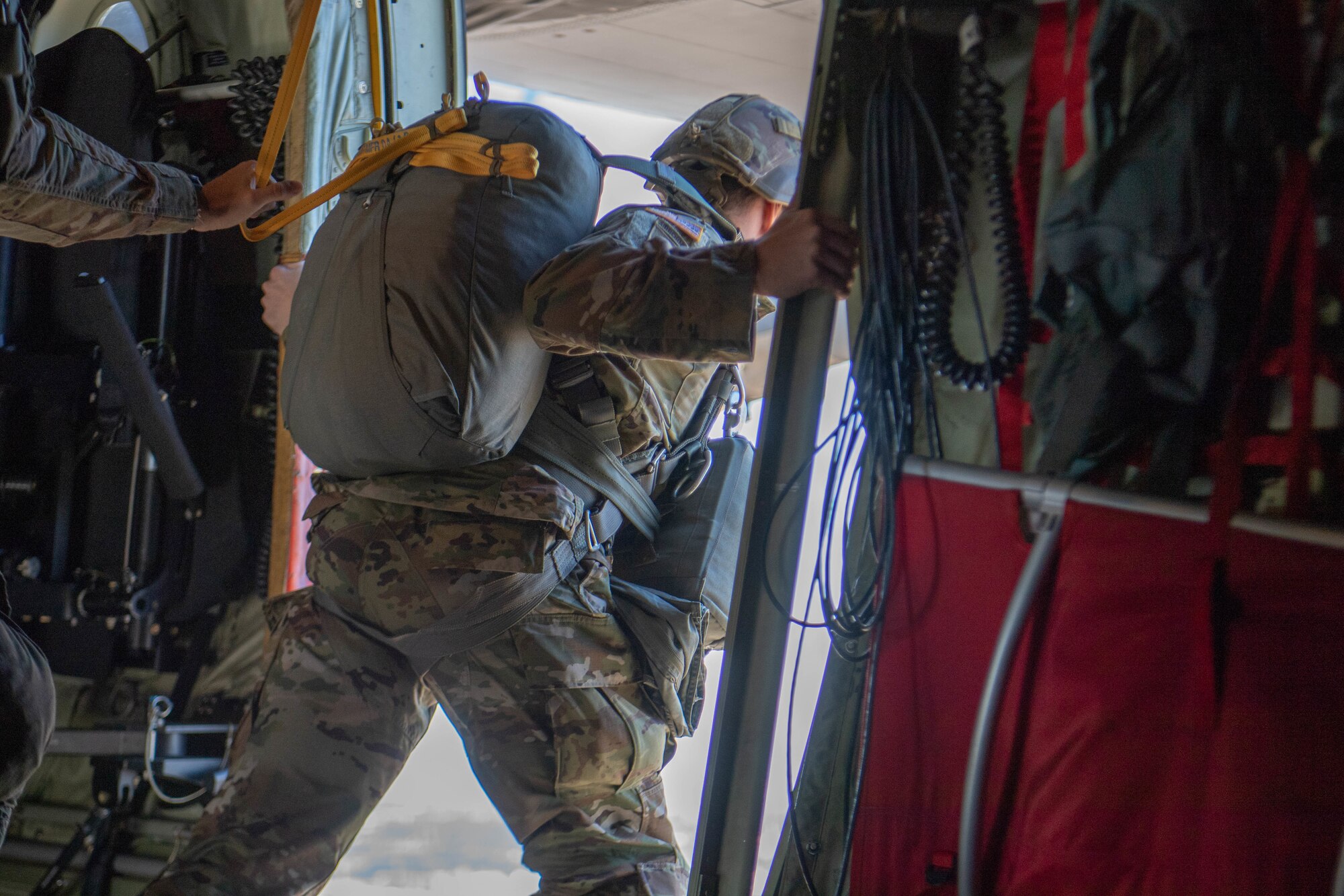 Soldier leans out side door midair aboard U.S. Air Force C-130J Super Hercules.