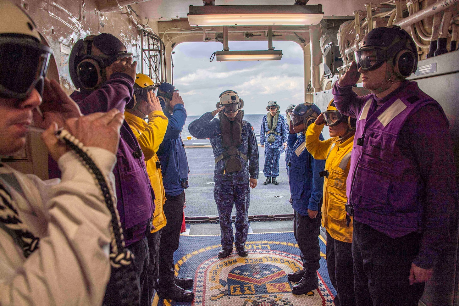 Japan Maritime Self-Defense Force (JMSDF) Rear Adm. Shirane Tsutomu, commander, JMSDF Mine Warfare Force, salutes sideboys during an underway visit to amphibious assault ship USS America (LHA 6).