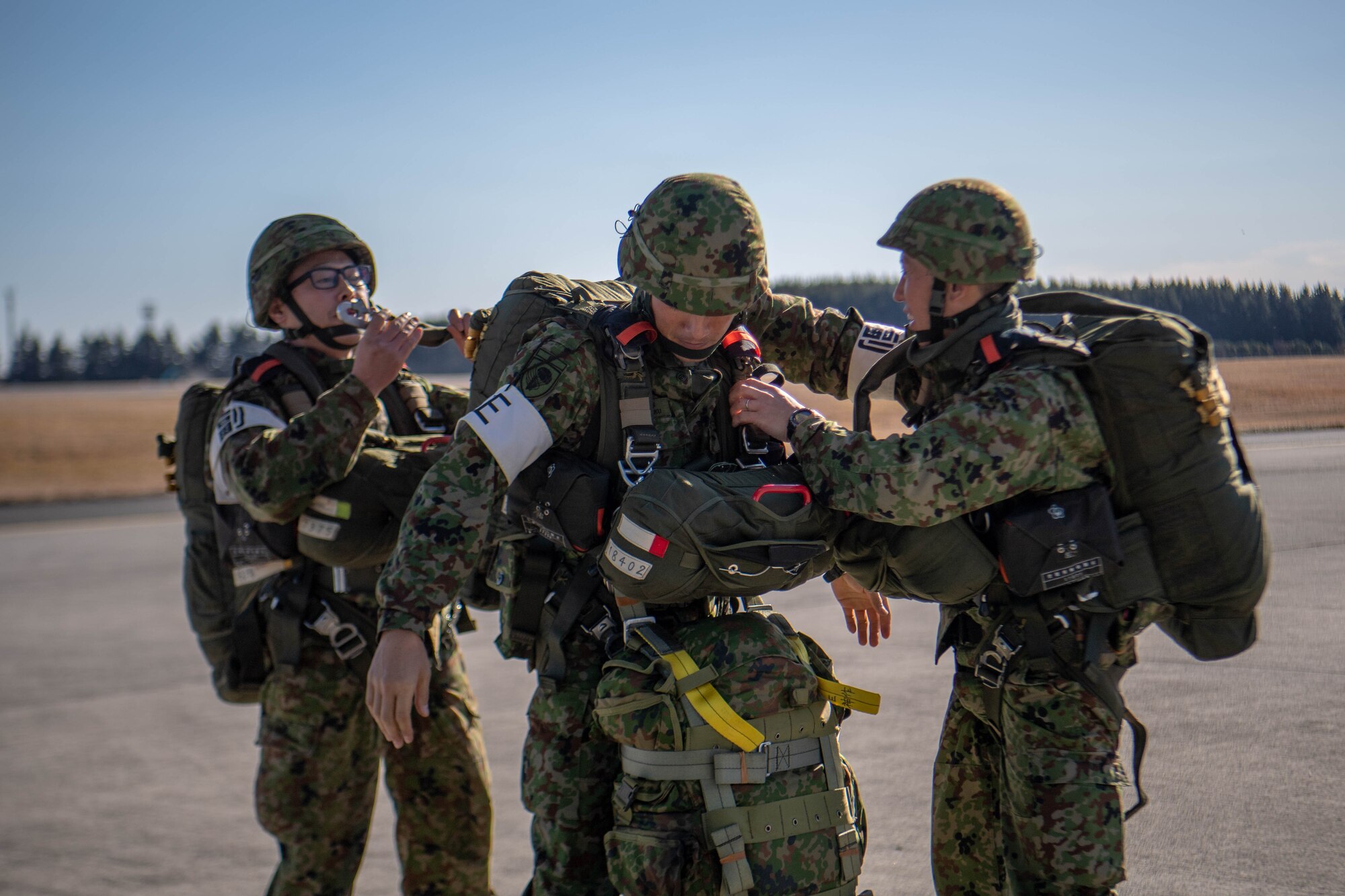 JGSDF Soldiers adjust parachute harness.