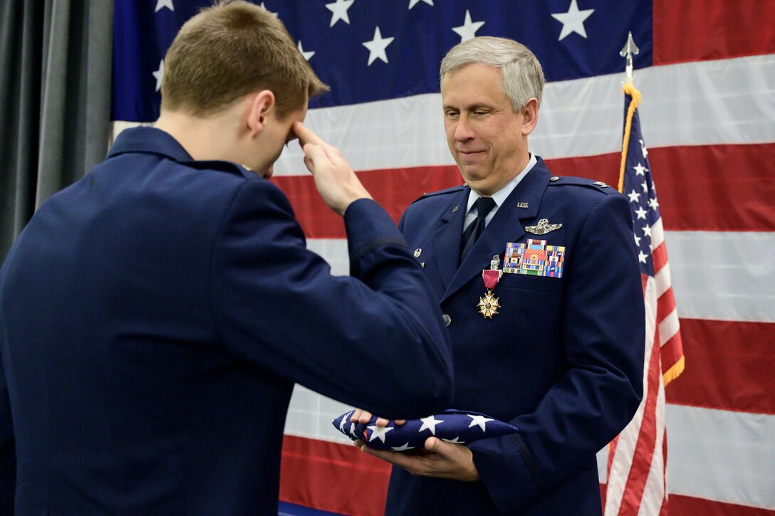 Lt. Burgess salutes flag as Col. Burgess holds it.