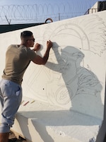 Sgt. Angel Bastidas-Pineda, a transportation land movement non commissioned officer, 103rd Expeditionary Sustainment Command, lays down the first outline of the final t-wall at Camp Arifjan, Nov. 4, 2019. (U.S. Army courtesy photo)