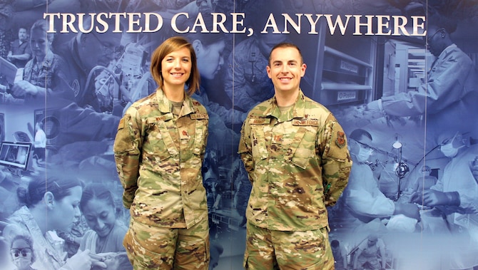 Image of two Airmen standing in front of a mural.