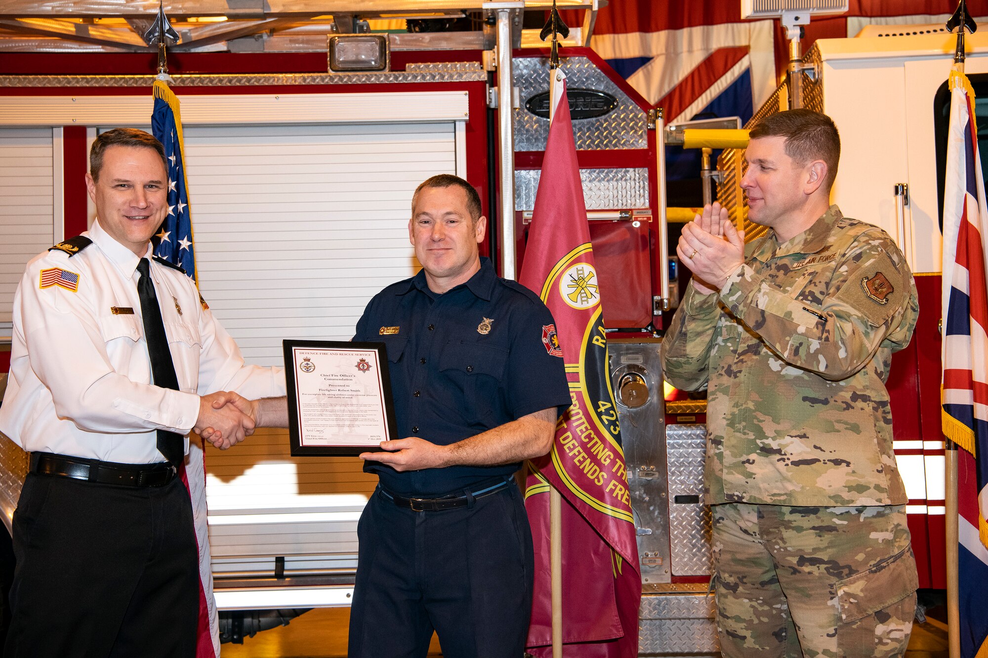 Robert Smith, center, 423rd Civil Engineer Squadron firefighter, receives a Chief Fire Officer’s commendation at RAF Alconbury, Dec. 20, 2019. Smith was recognized for exemplary lifesaving abilities under extreme pressure and clarity of mind for actions performed on August 21st. Smith administered CPR to his wife Karen for 17 minutes until paramedics arrived at his home. (U.S. Air Force photo by Senior Airman Eugene Oliver)