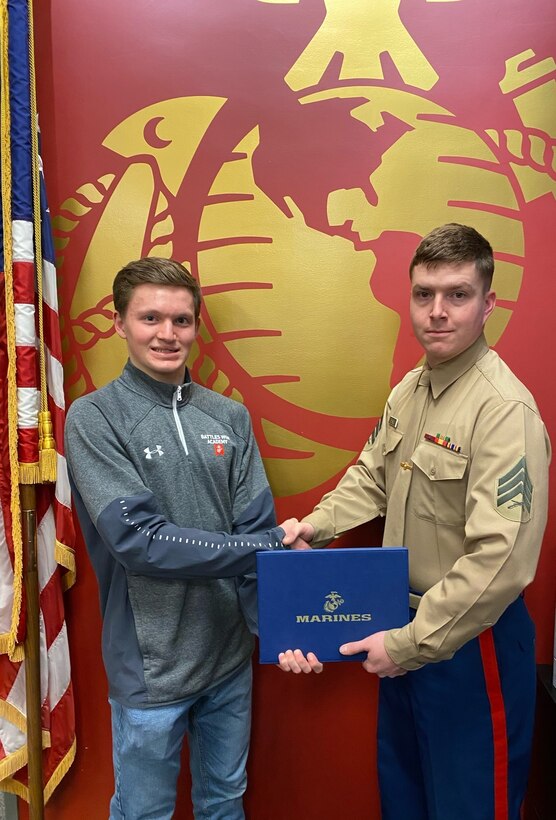 Avery Peterson receives a certificate of achievement for completing of the 2019 Battles Won Academy from Sgt. Myles A. Grissom at Marine Recruiting Substation Eugene, Oregon, December 16, 2019. The Battles Won Academy hosts young men and women as well as their mentors, who excel in athletics, but have also shown themselves to be leaders in the classroom and in their hometowns.