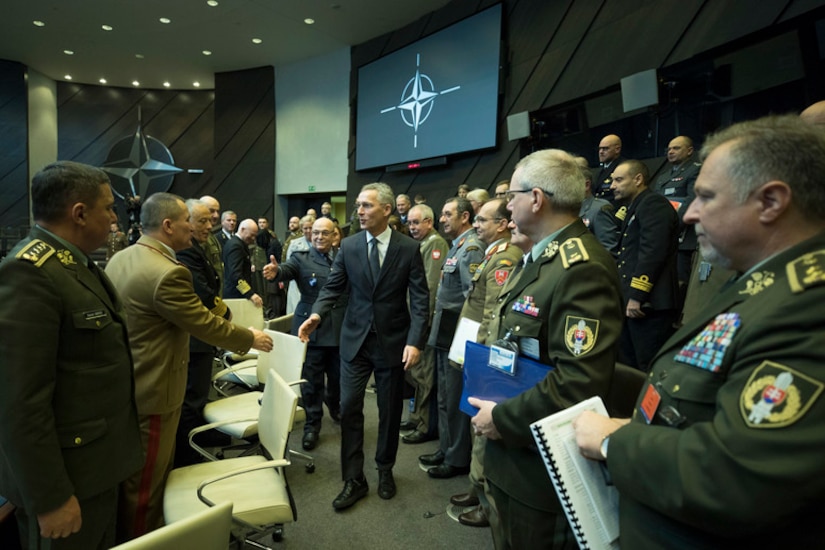 Army general and civilian man in a suit shake hands.