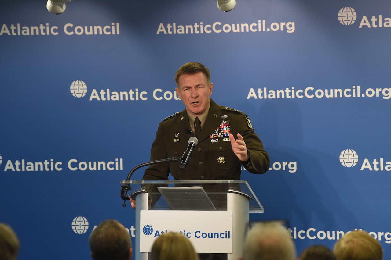 A military officer speaks from behind a podium.