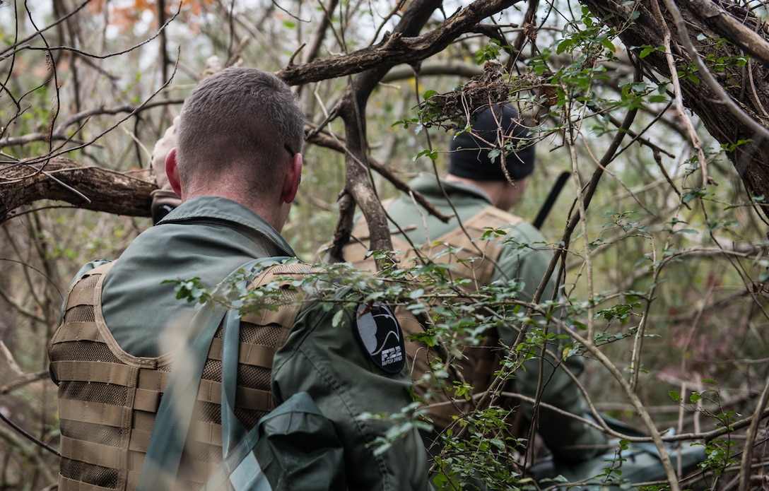 U.S. Air Force Lt. Col. Jonathan Kuntz, 633rd 1st Operations Support Squadron director of operations, and Capt. Nathan Miller, 94th Fighter Squadron instructor pilot, walk stealthily through the woods during a training at Joint Base Langley-Eustis, Virginia, Dec. 12, 2019. The training taught skills needed to survive in the event of an isolation situation. (U.S. Air Force photo by Airman 1st Class Sarah Dowe)