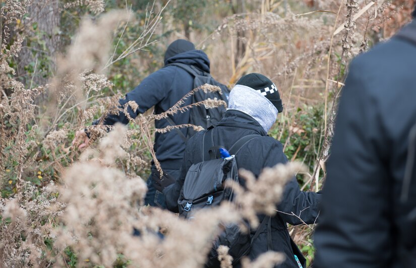 Volunteers simulating hostile individuals, search a field for U.S. Air Force personnel during a training at Joint Base Langley-Eustis, Virginia, Dec. 12, 2019. The training taught participants camouflaging, evasion and other skills necessary in the event of an isolating situation. U.S. Air Force photo by Airman 1st Class Sarah Dowe)