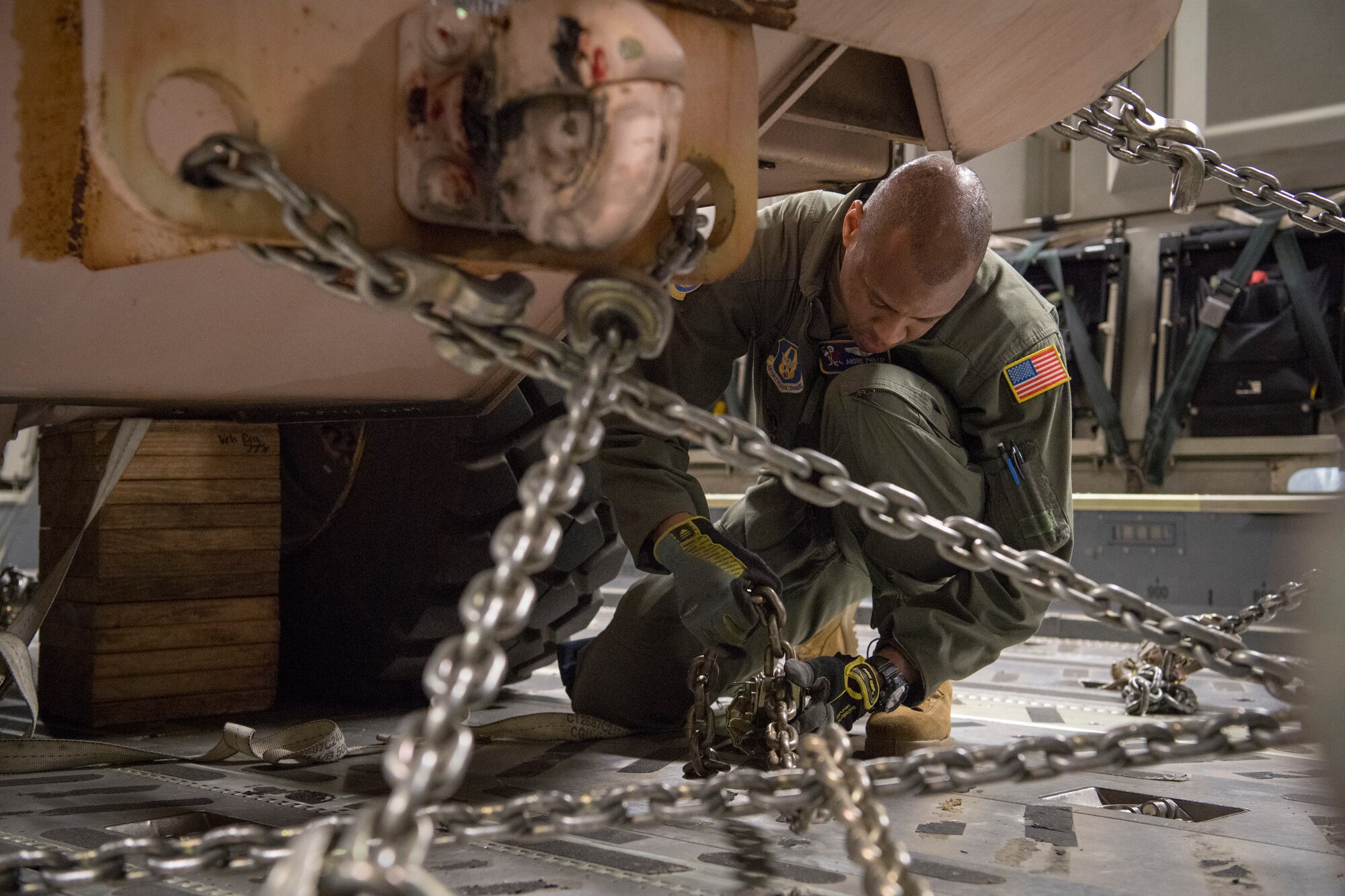 U.S. Air Force Staff Sgt. Andre A. Phillip, a C-17 Globemaster III loadmaster with the 732nd Airlift Squadron, 514th Air Mobility Wing, Joint Base McGuire-Dix-Lakehurst, N.J., tightens chains to secure a forklift to the aircraft prior to take-off, Jan. 10, 2020. Loadmasters must also adjust chains midair due to movement after take-off. (U.S. Air Force photo by Senior Airman Ruben Rios)