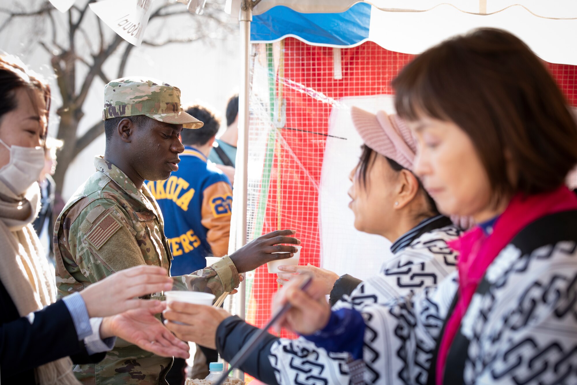 Japanese employees serve complimentary Ozoni, a Japanese traditional New Year soup containing rice cakes, and Oshiruko, a red bean soup with rice cakes, to members of Team Yokota.