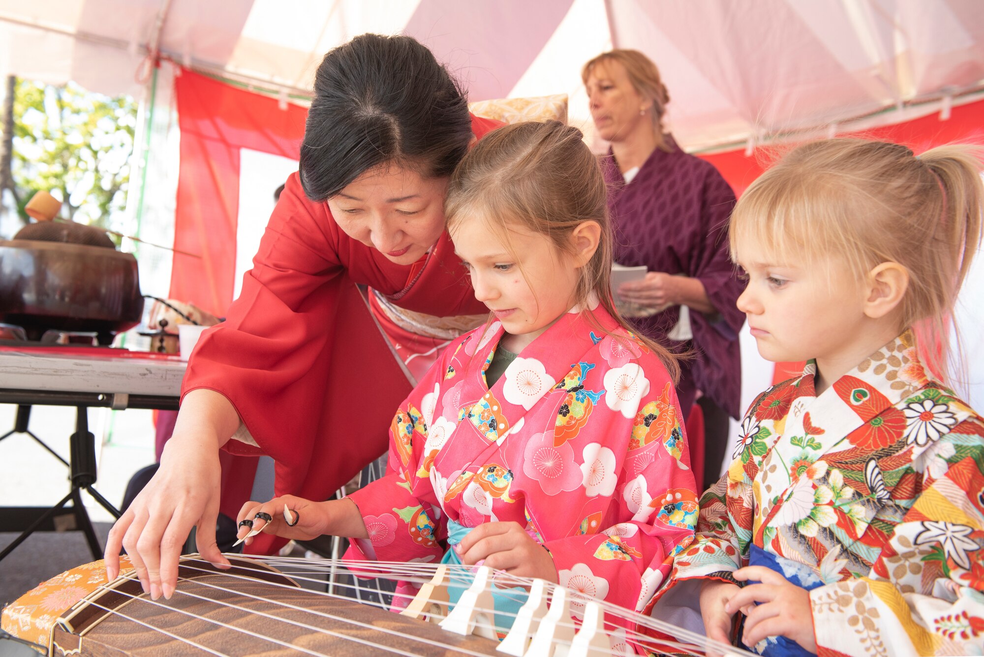Children learn how to play the Koto, a traditional Japanese harp, from a Japanese employee during the New Year Fest hosted by the Japanese Welfare Association, Jan.10, 2020, at Yokota Air Base, Japan.