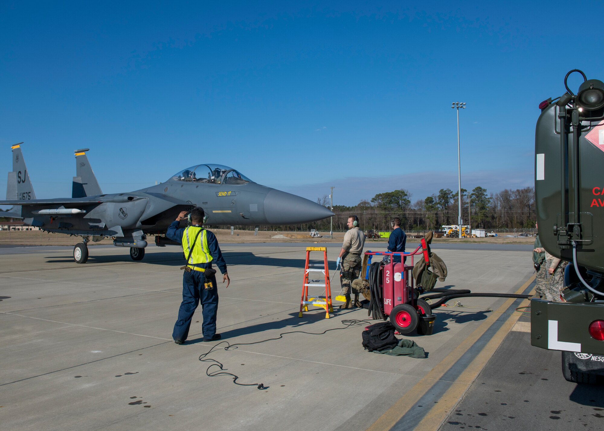 Airmen from the 4th Logistics Readiness Squadron marshal an F-15E Strike Eagle to an R-11 fuel truck for hot-pit refueling.