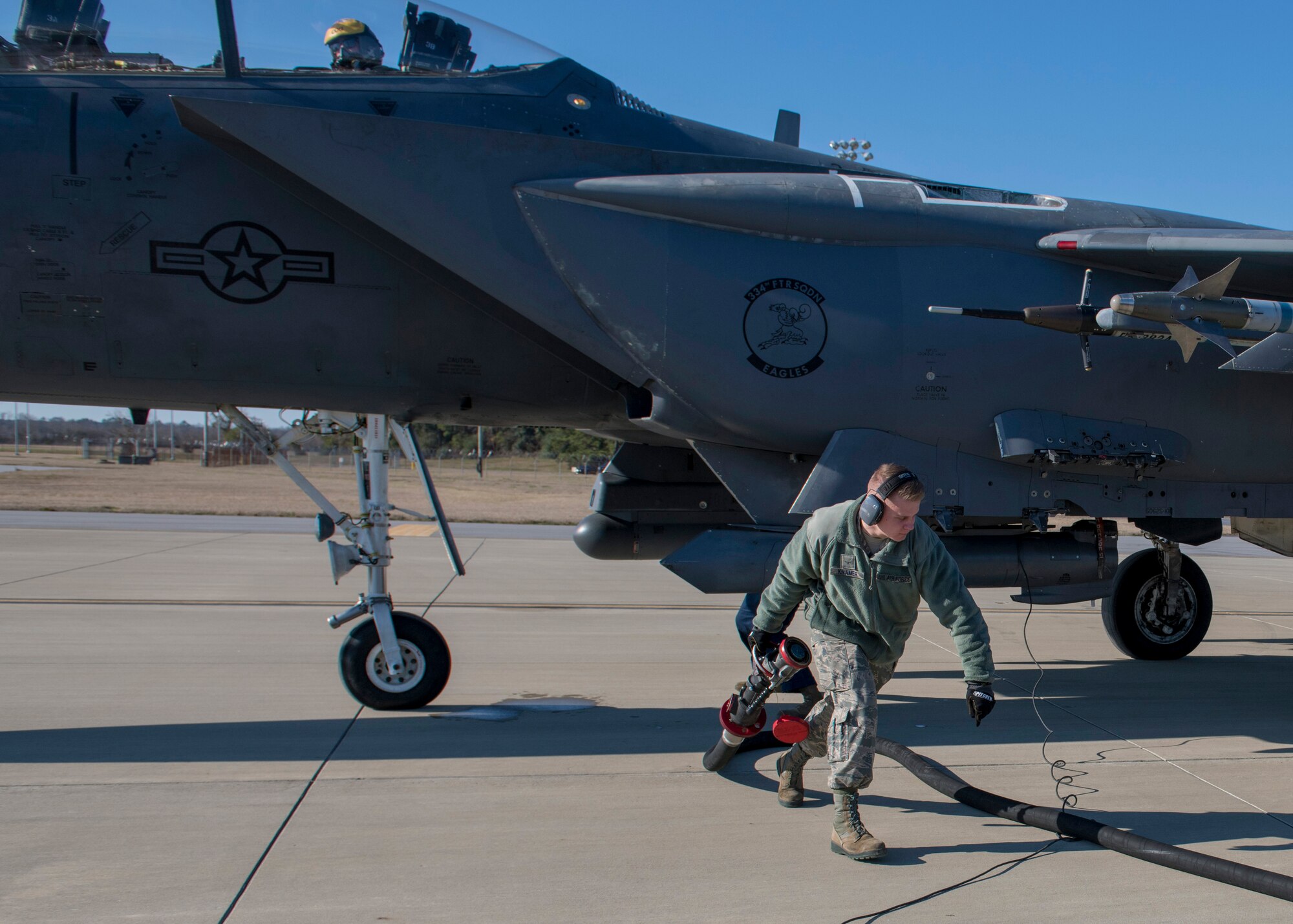 Airman Benjamin Kramer, 4th Logistics Readiness Squadron fuel distribution operator, carries a fuel nozzle after completing a hot-pit refueling of an F-15E Strike Eagle.